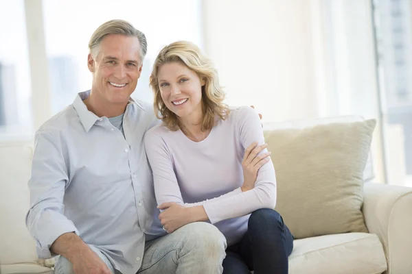 Happy Couple Sitting On Sofa In Living Room