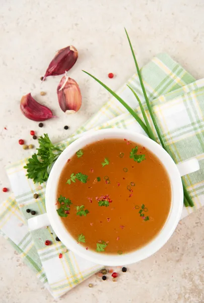 Bone Broth in Small Soup Bowl Served with Fresh Herbs, Garlic and Spices