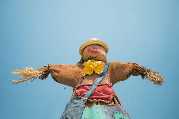 Cute colorful scarecrow under bright blue sky