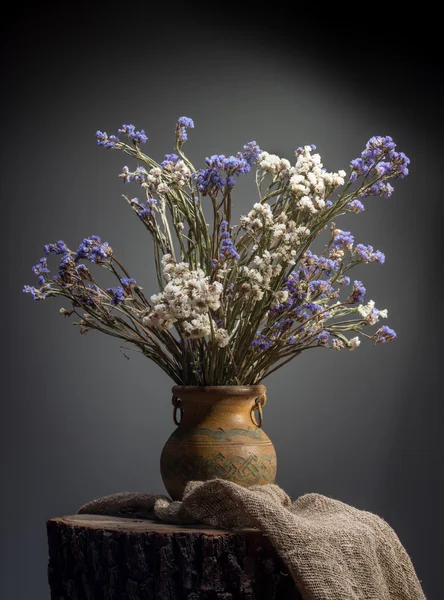 Bouquet of flowers in old vase on stump