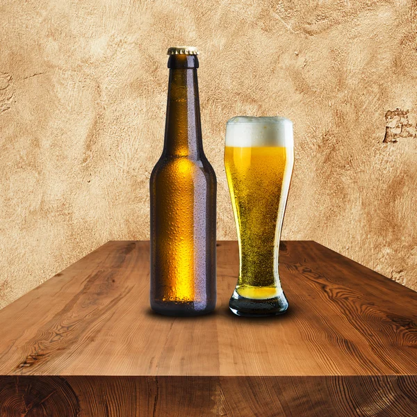 Bottle and glass of cold beer on wood table