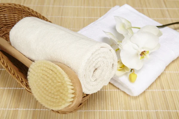 Bath brush and rolled towel in a basket