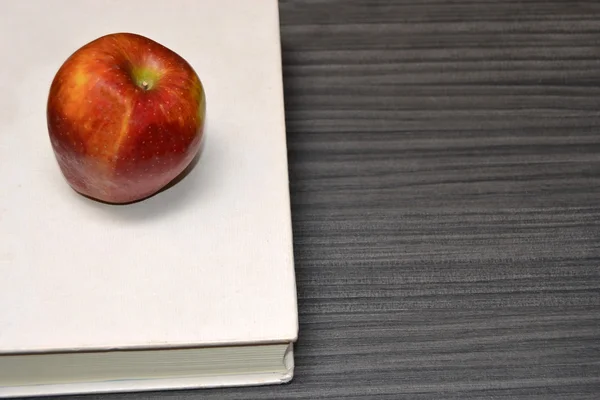 Book and apple on the wood