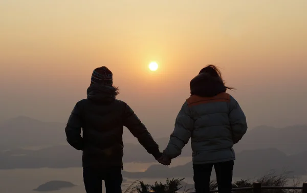 Boyfriend and girlfriend holding hand, hand in hand in the first day sunrise a new year on the peak landscape with beautiful skyline in good morning background