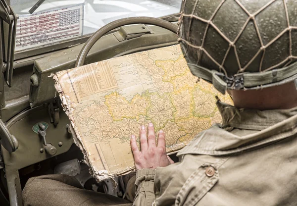 Driver of a military vehicle look at a map of Normandy