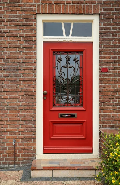 Red door with wrought-iron bars on the brick wall of a house