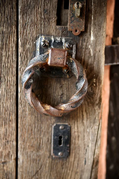 Old rusty metal ring on the handle of an old wooden door, rusty keyhole well