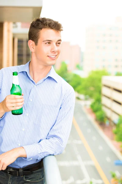 Closeup portrait of handsome guy drinking his beverage on outside balcony