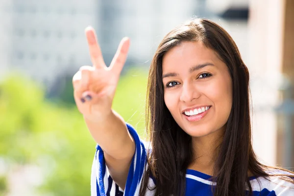 A close-up picture of a beautiful happy woman giving a victory sign relaxing on a summer day on a balcony of a new apartment
