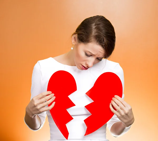 Confused woman holding broken heart
