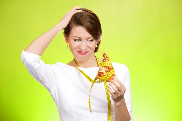 Woman looking at fatty pizza with measuring tape around