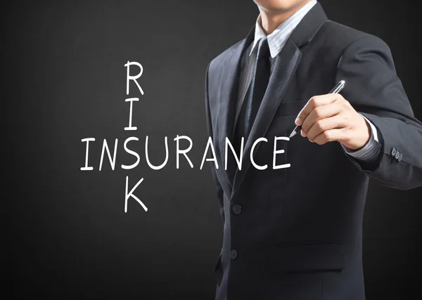 Business man writing Risk Insurance crossword