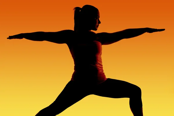 Silhouette of fit yoga model with orange and yellow background