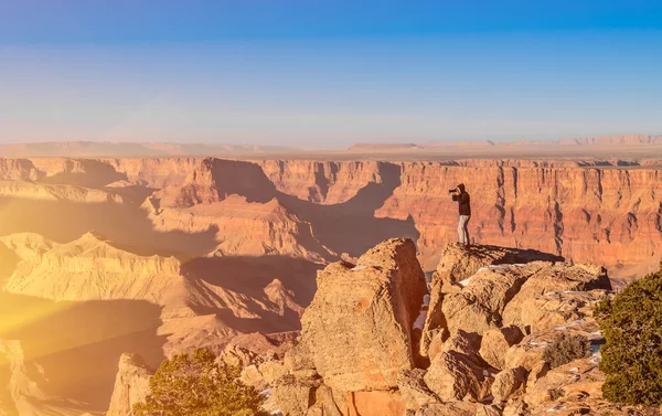 Adventurous man taking a photo at Grand Canyon before sunset