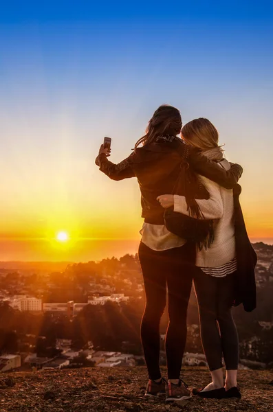 Couple of young women best friends taking a selfie during sunset