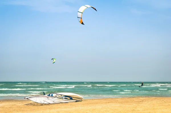 Kite surfing in desert windy beach with windsurf board - Exlcusive adventures in tropical destinations worldwide