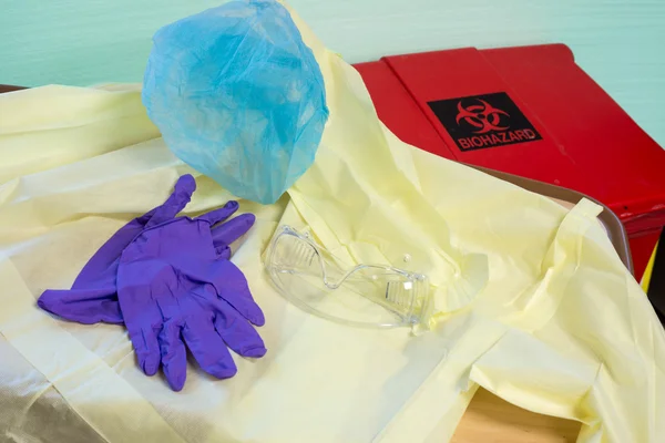 Disposable hospital gown, gloves, hair cover and goggles next to