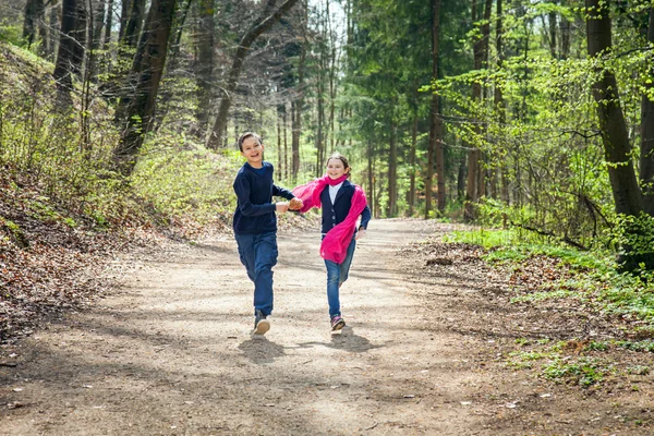 Brother and Sister running in a forest hand in hand