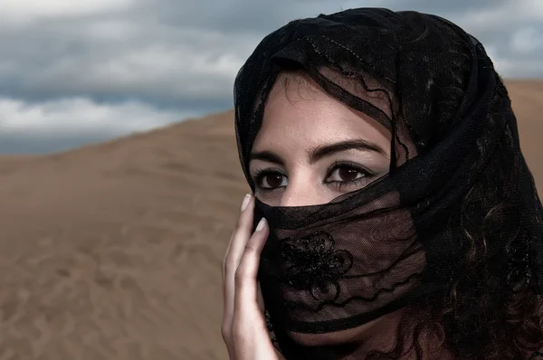 Woman in paranja in desert dunes
