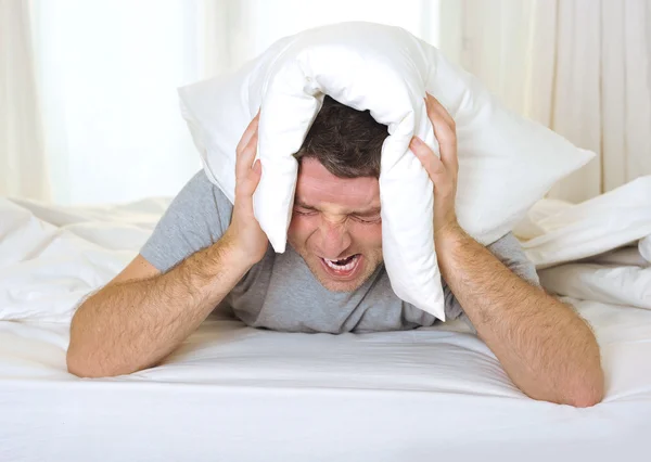 Man suffering hangover and headache with pillow on his head