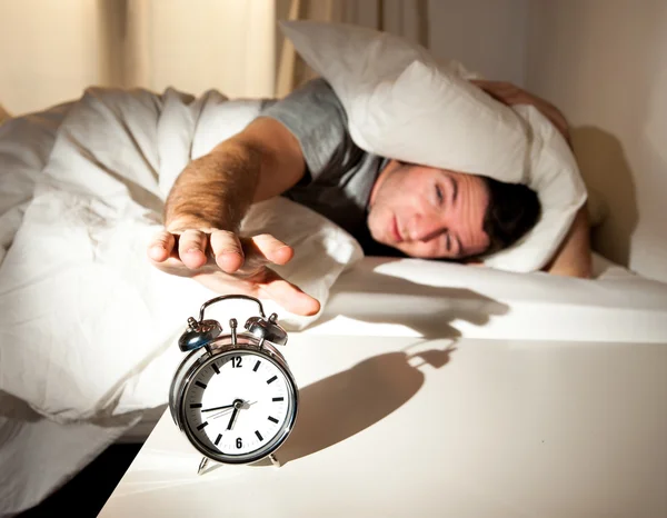 Sleeping man disturbed by alarm clock early morning
