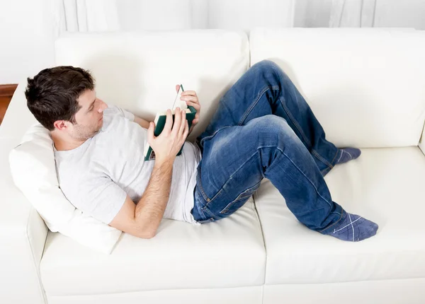 Attractive man reading book or studying on couch