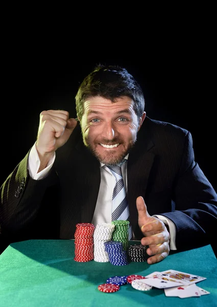 Happy man grabbing poker chips after winning bet gambling