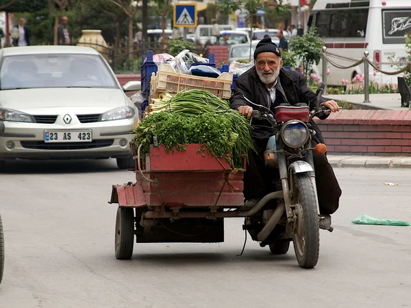 Old meets new on the streets of Turkish city. Grocer transporting his vegetables to bazaar market.