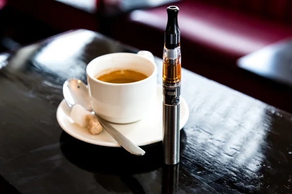 Espresso coffee with an e-cigarette in a pub