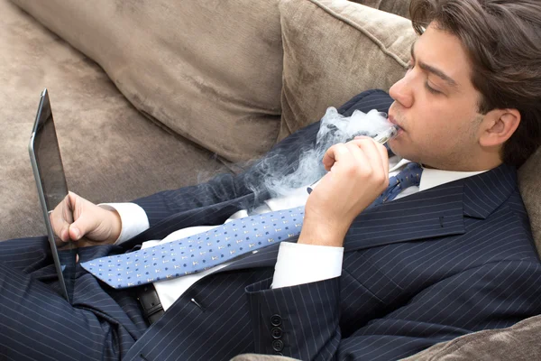 Businessman relaxing on a sofa smoking and working