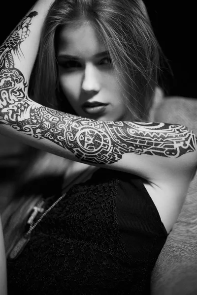 Pretty female with tattoos looking at camera