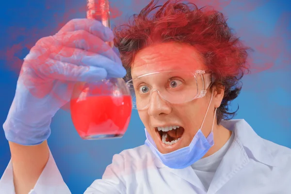 Scientist looks at flask with red liquid