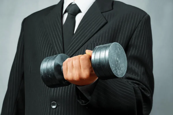 Strong businessman with metal dumbbell