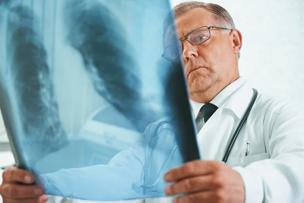 Older doctor is analyzing x-ray image