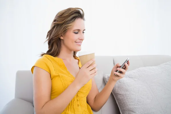 Smiling woman sitting on sofa holding coffee