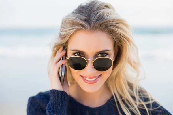 Cheerful gorgeous blonde on the phone looking over her sunglasse