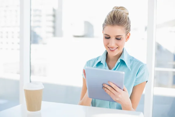 Smiling classy woman using tablet while having a break