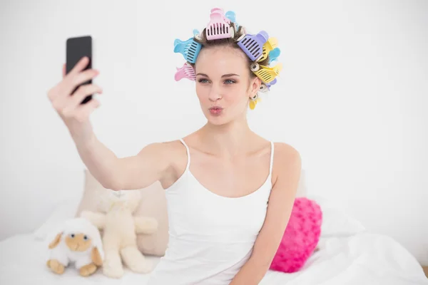 Funny woman in hair curlers taking a picture