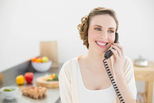 Cute peaceful woman phoning with a telephone in her kitchen