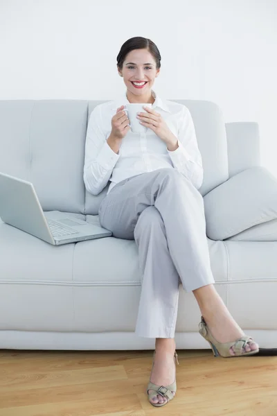 Full length of a smiling well dressed woman with laptop and coff