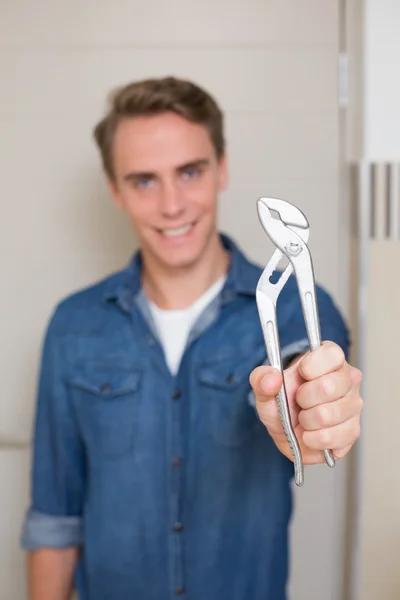 Smiling young handyman holding out wrench
