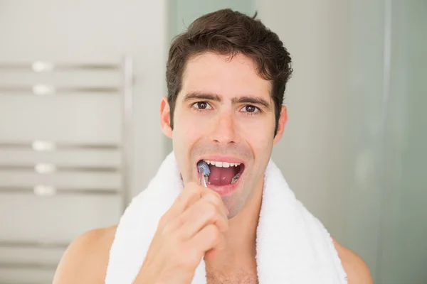 Close up portrait of man brushing teeth in bathroom