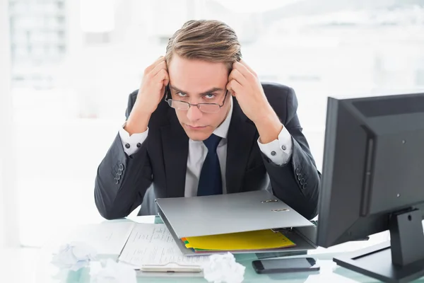 Worried businessman with documents at office desk
