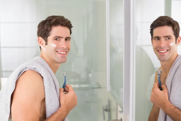 Smiling handsome man shaving in bathroom