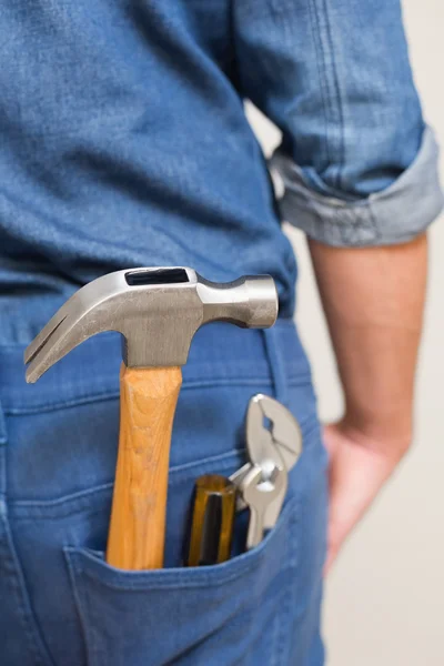 Several tools in a man\'s rear denim pocket