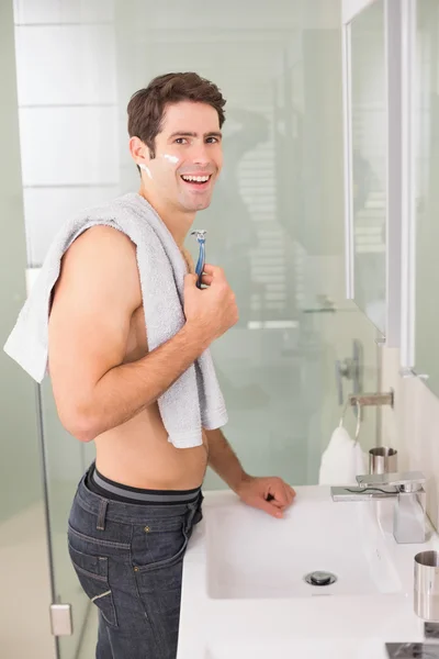 Smiling handsome man shaving in bathroom