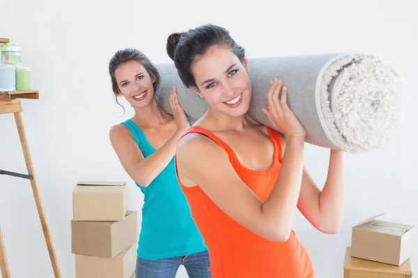 Friends carrying rolled rug after moving in a house