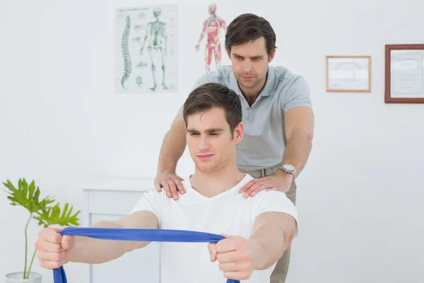 Male therapist assisting man with exercises in office