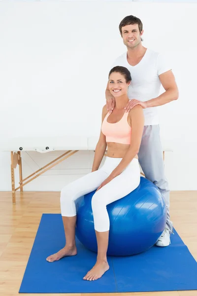 Woman on yoga ball working with physical therapist