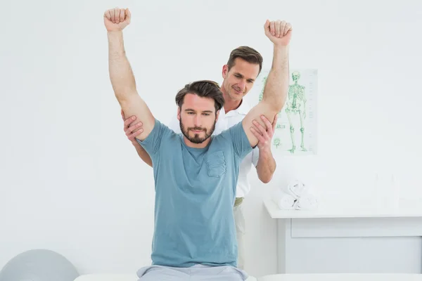 Male physiotherapist stretching a young man\'s arms